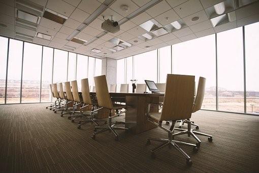 A board room with a table, chairs, and overhead projectors