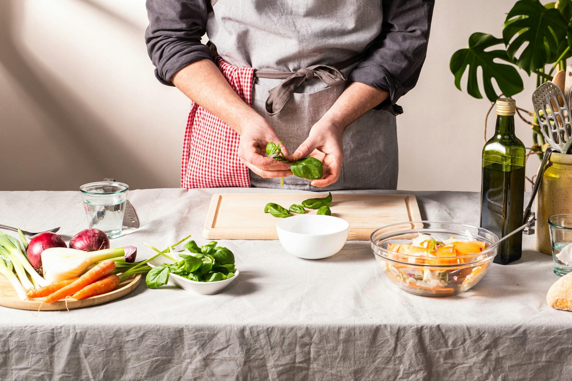 A chef preparing some basil for a dish.