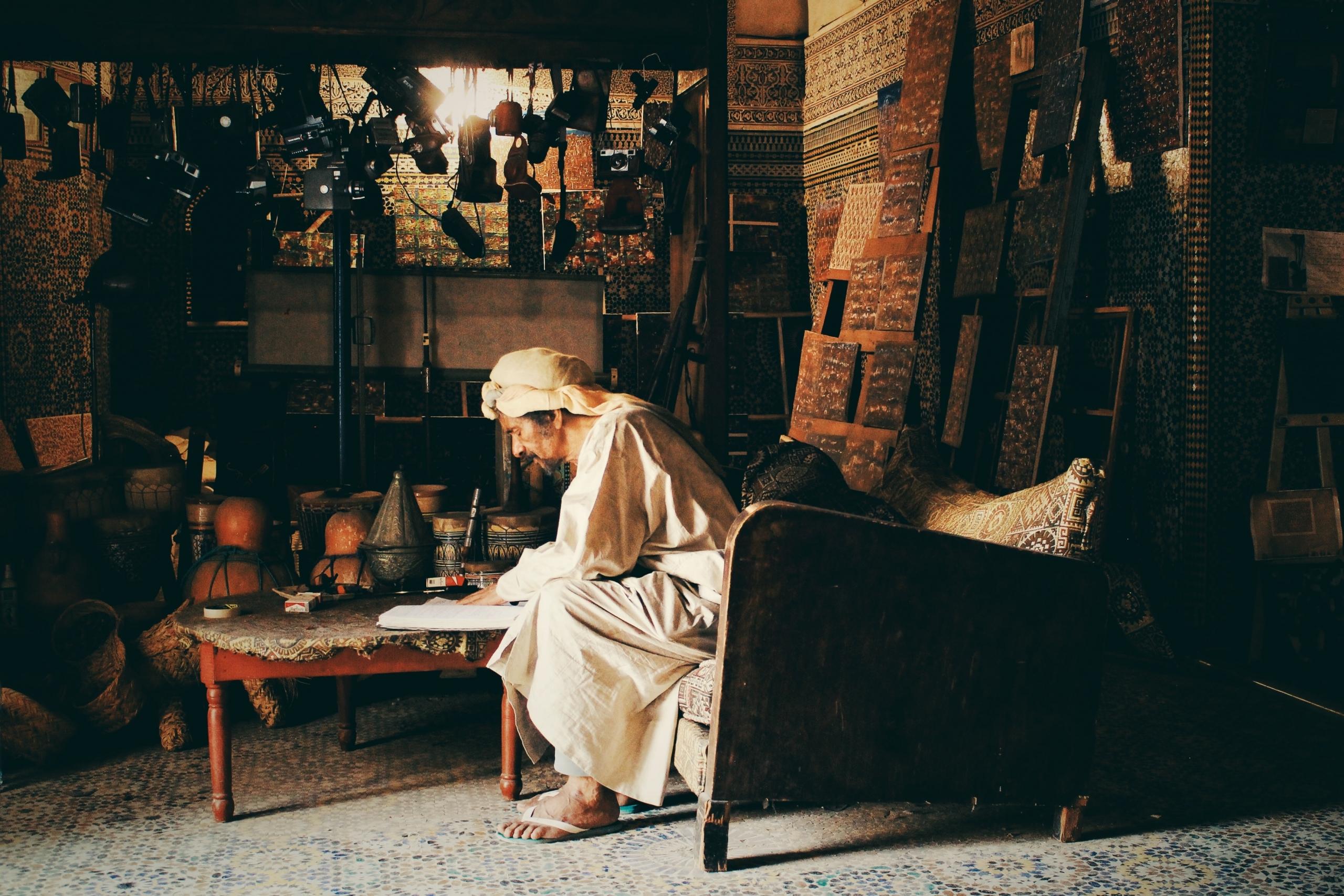 An Arab person sitting on the couch as they write