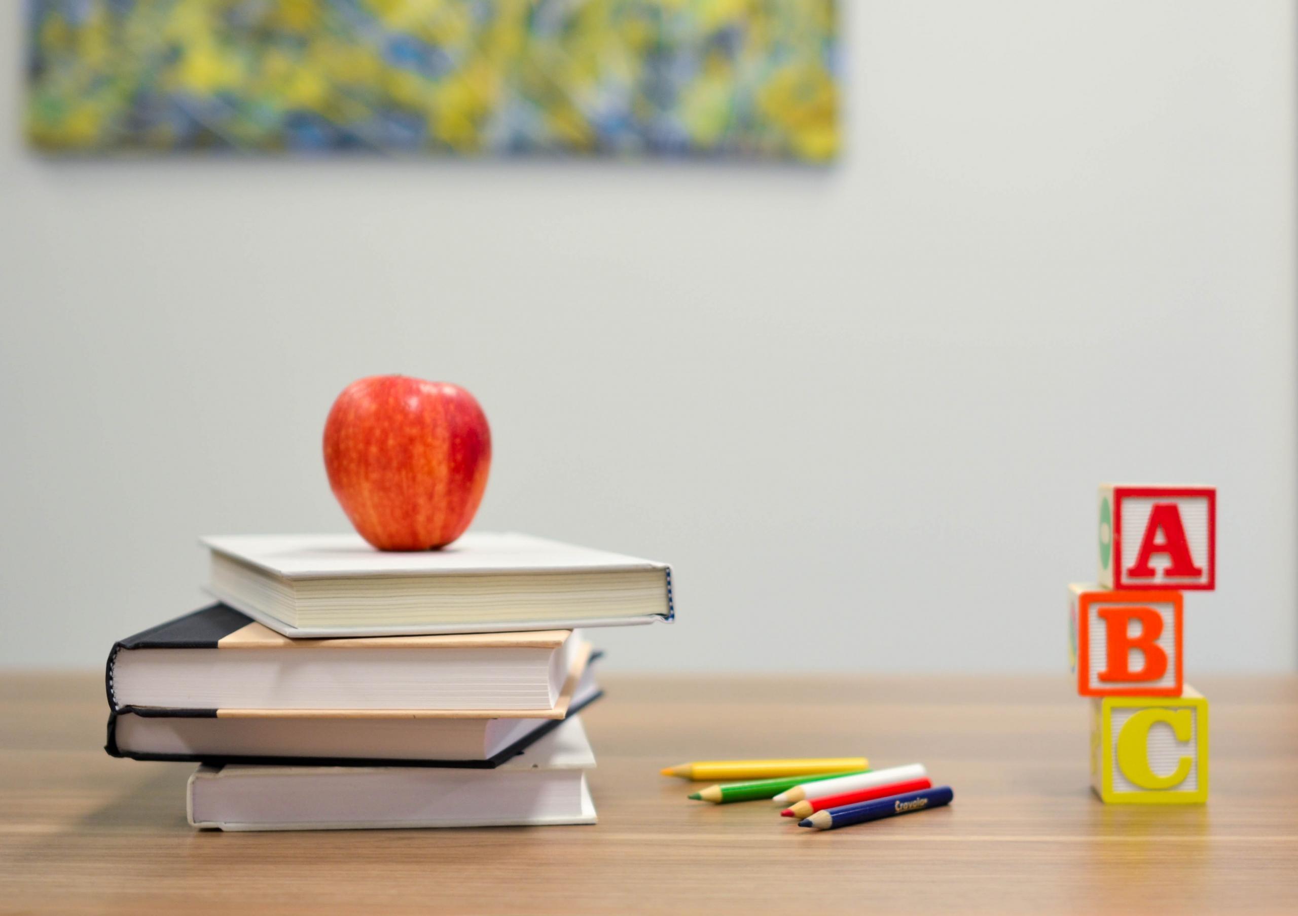A table with books, an apple, and letter blocks on it
