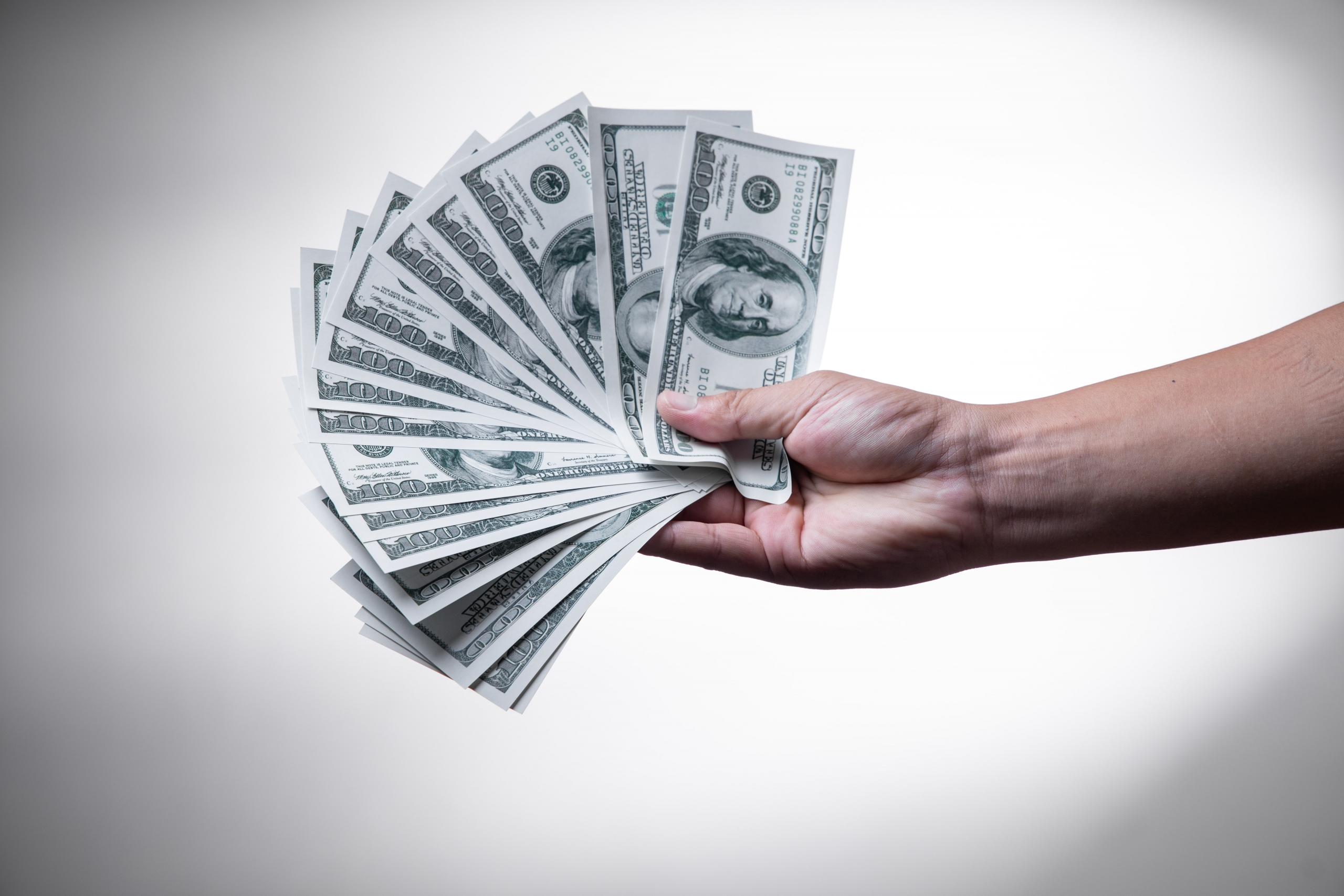 a hand with one hundred dollar bills