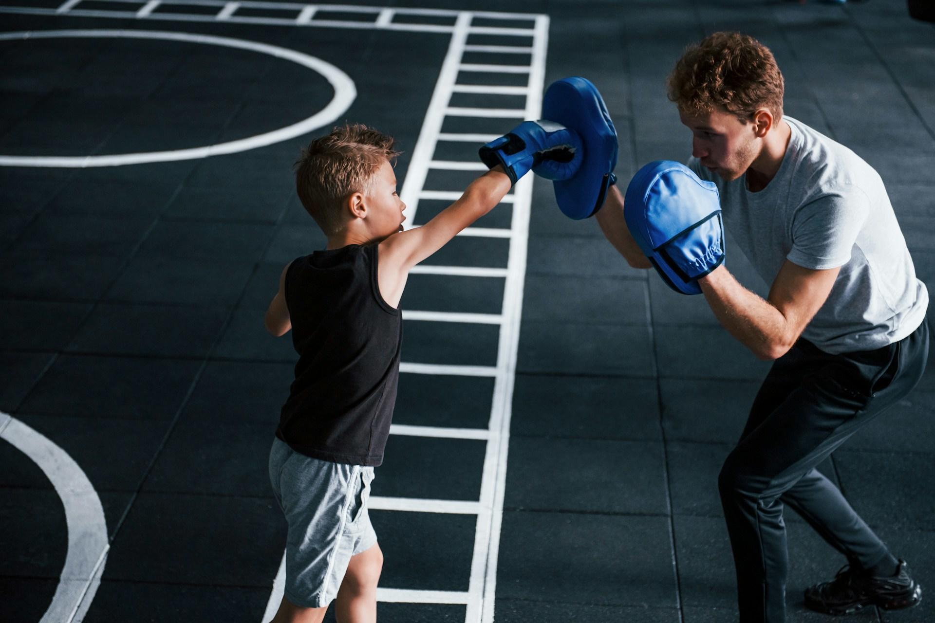 A kid boxing with a boxing tutor