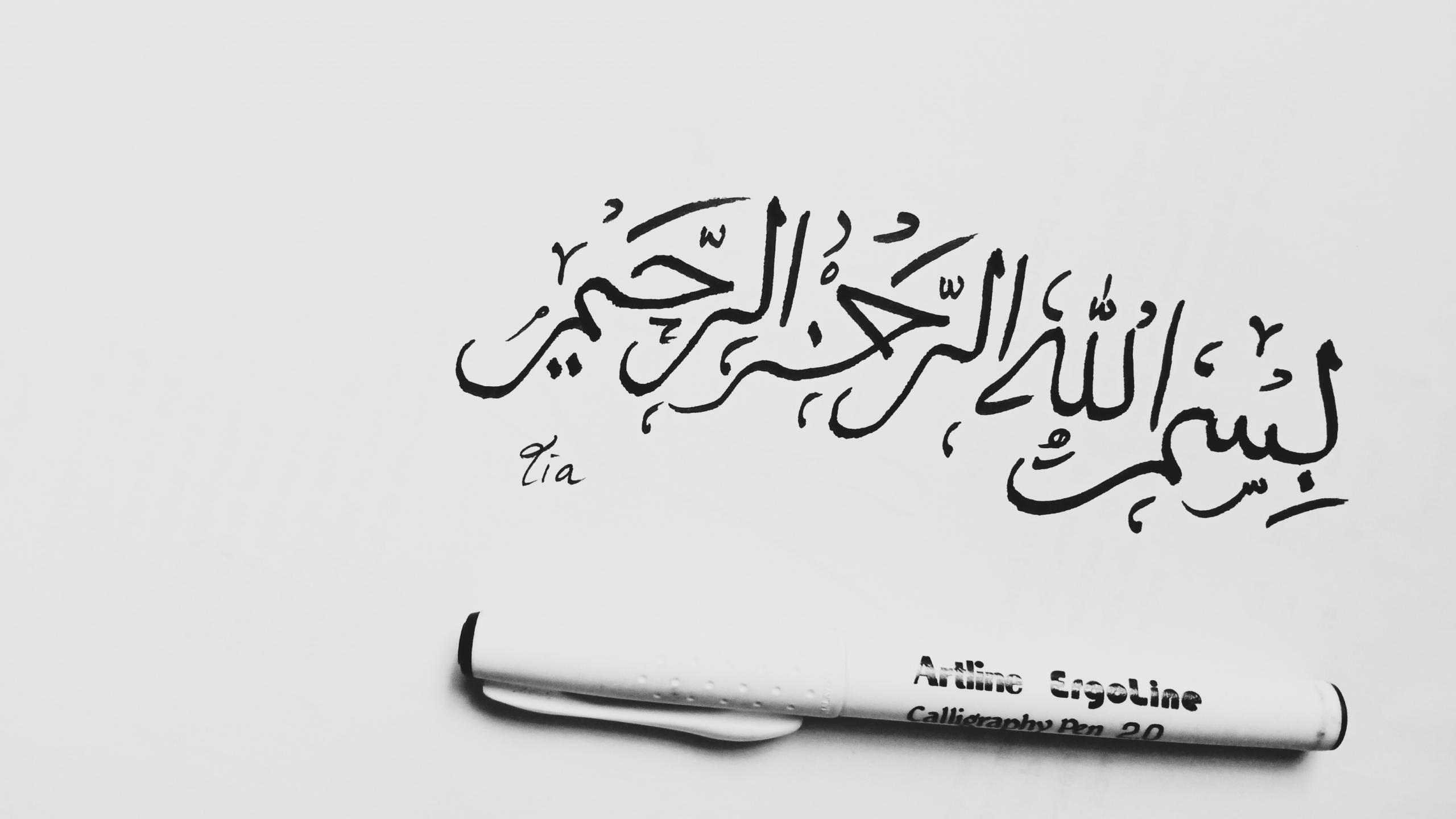 A calligraphy pen on paper with Arabic words written on it