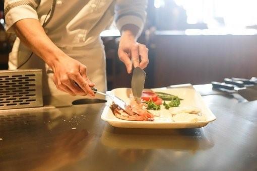 A chef plating a steak with a knife