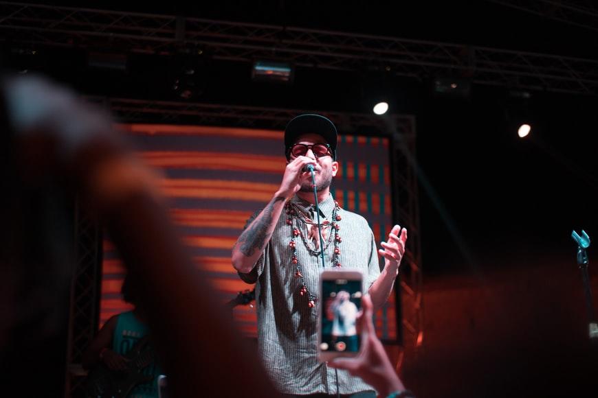 A rapper performing and someone from the audience recording his performance.