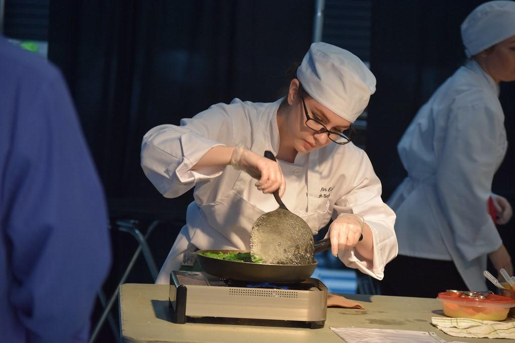 Student in culinary school preparing a dish to serve their instructor