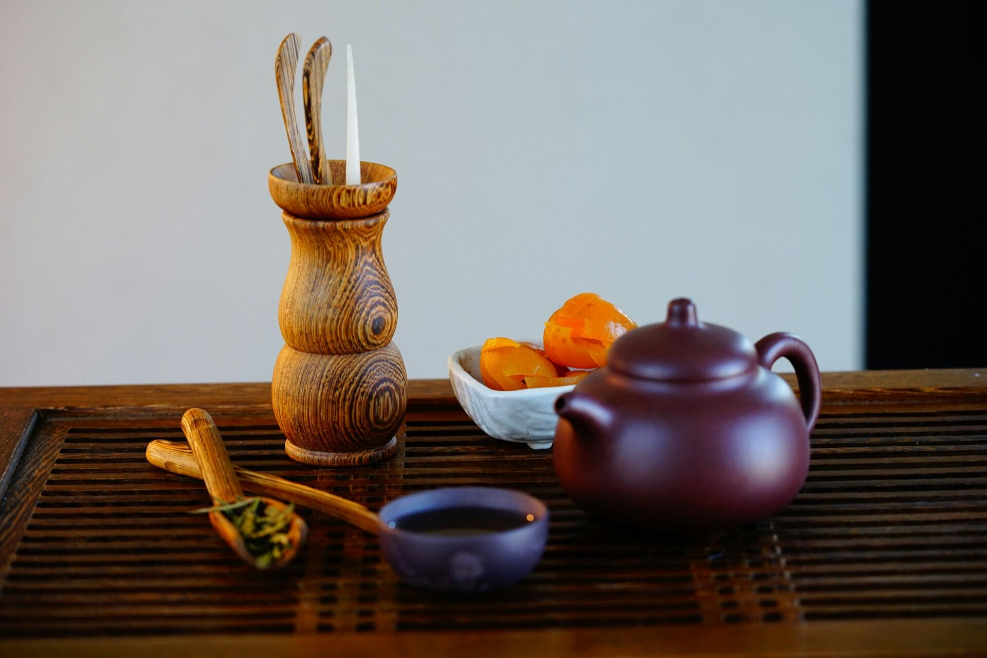 Wooden utensils in front of a teapot.