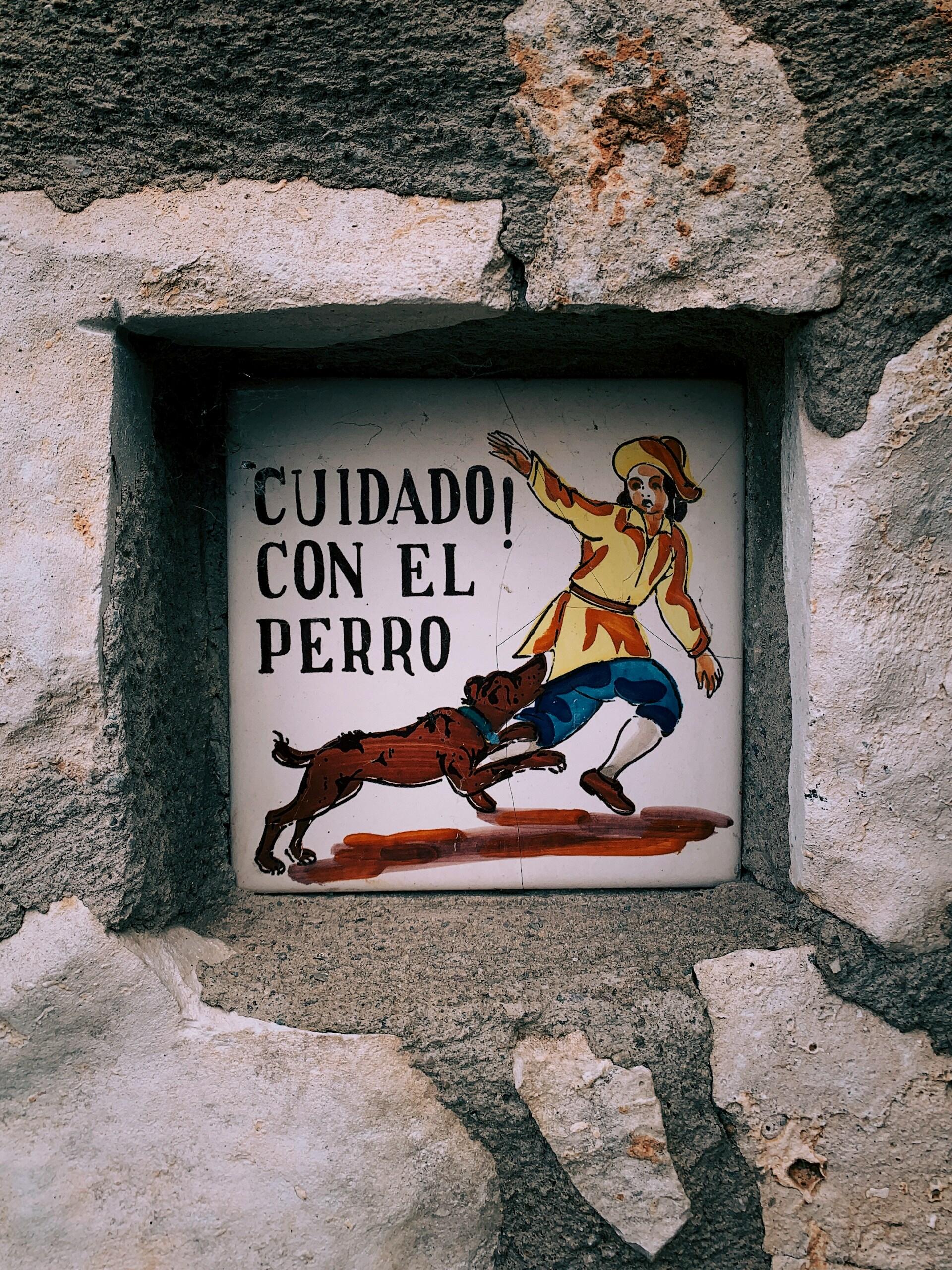 A sign warning people of a dog in Spanish.