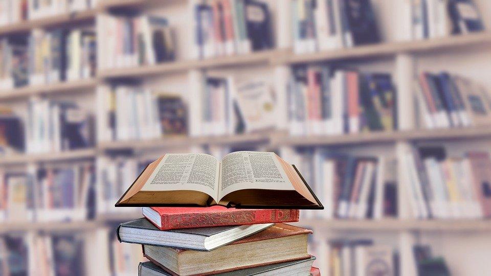 Library book open with shelves full of books in the background