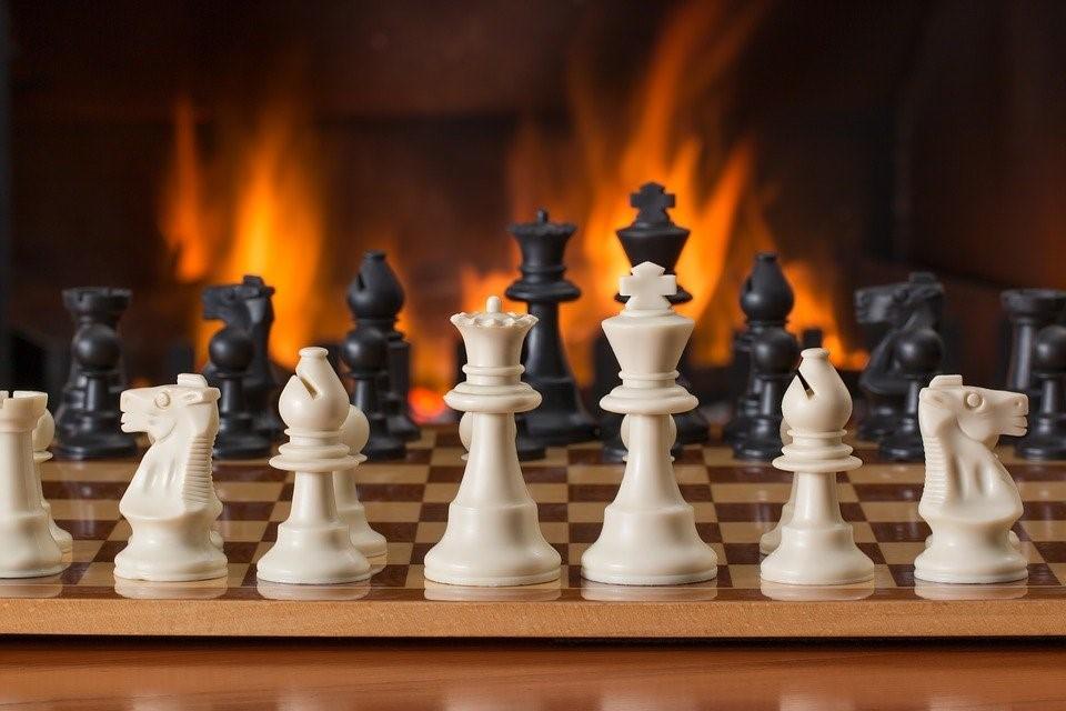 A set chessboard in the foreground, with fire in the background