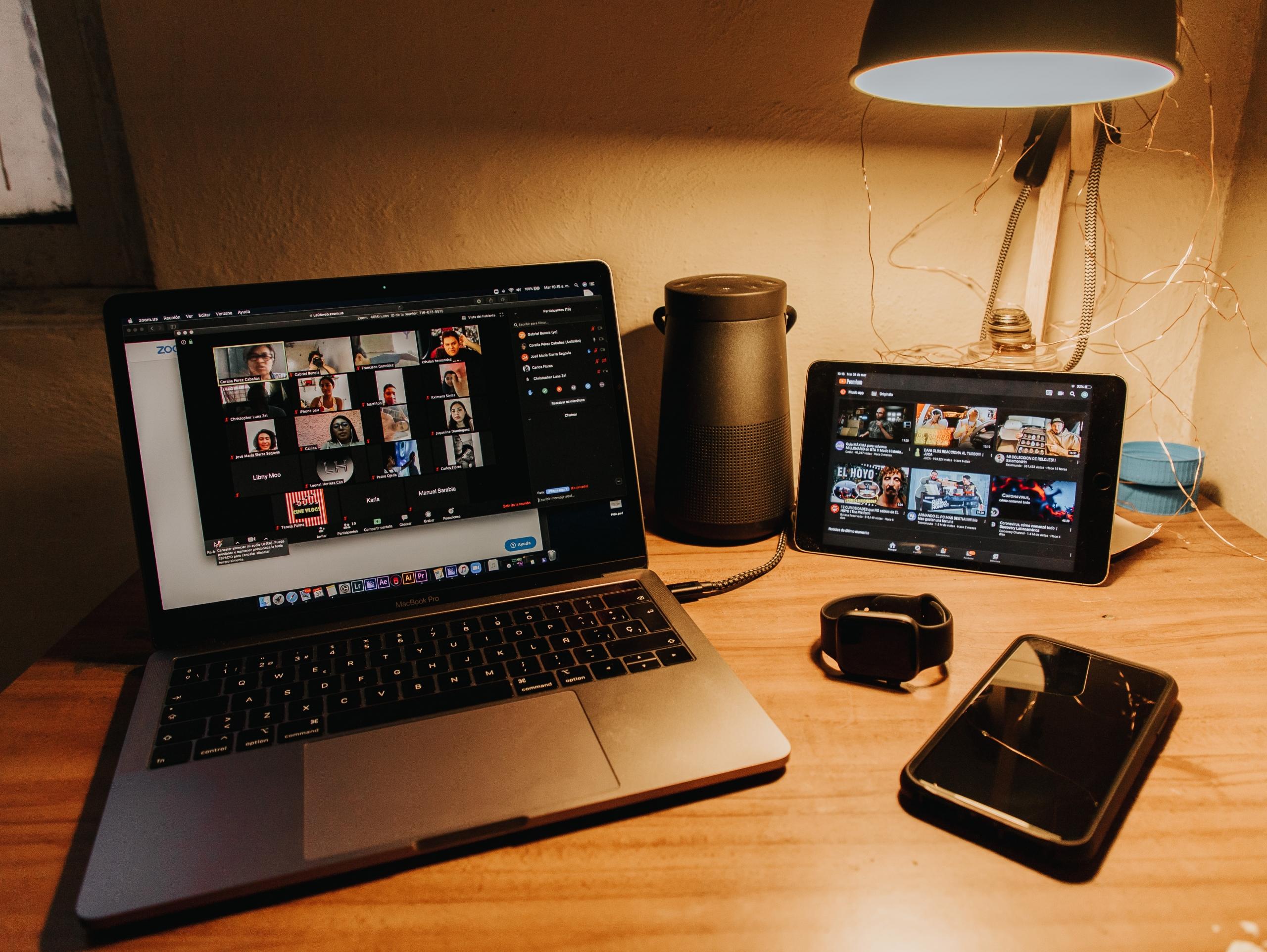 A computer, tablet, Apple Watch, and phone on a desk.