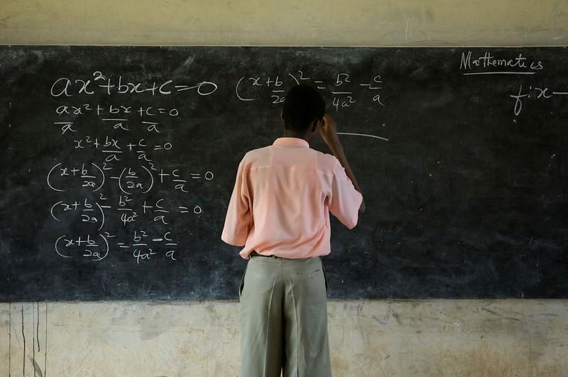 A teacher solving math equations on a blackboard