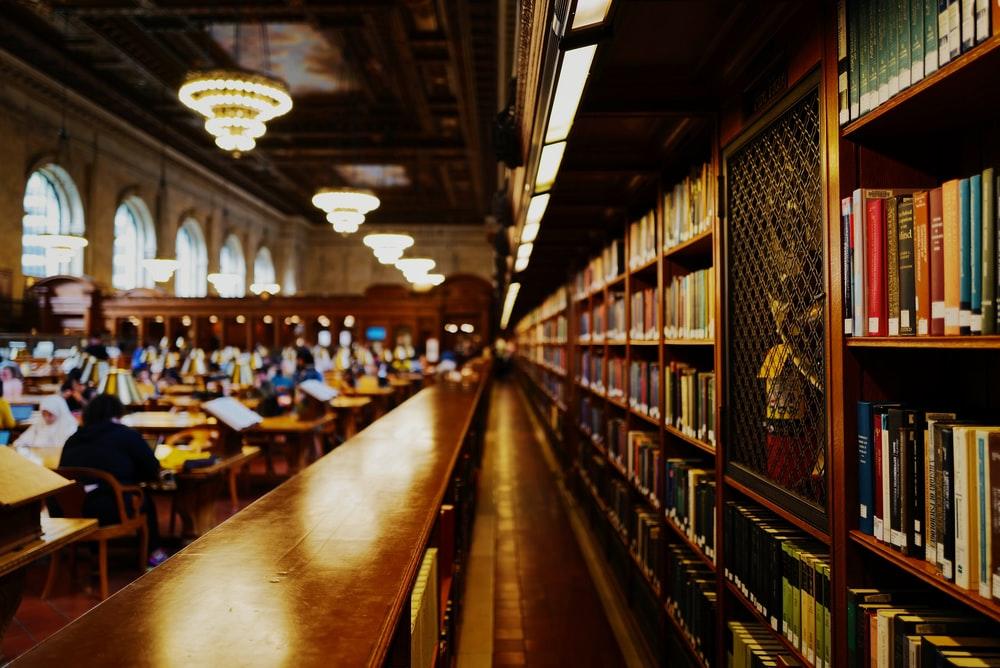 A shelf of books and a bunch of people in a study area