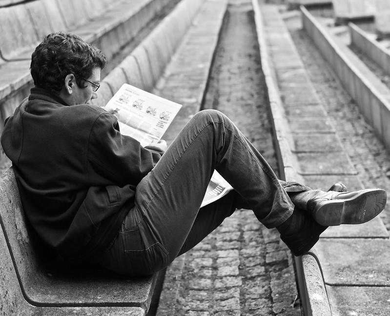 A person reading a French newspaper
