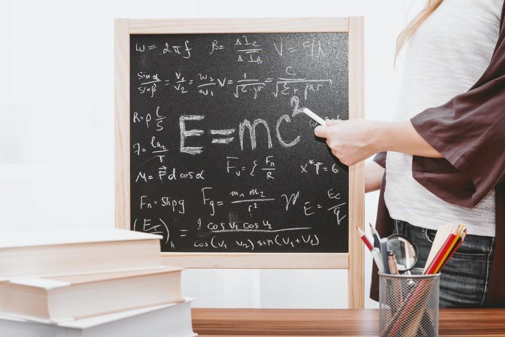 A lady pointing at an algebraic equation with a chalk
