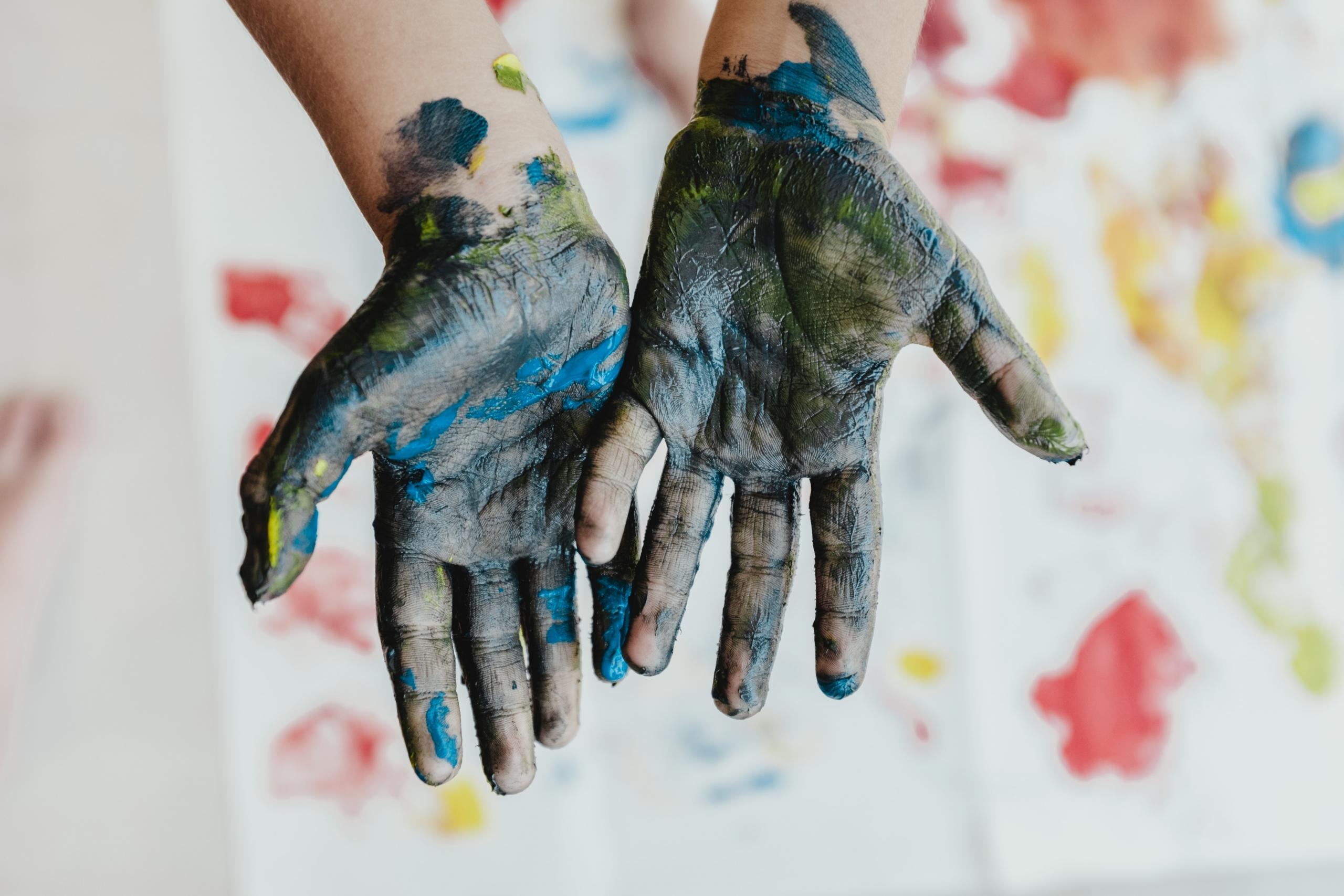 : A child’s hands covered in paint