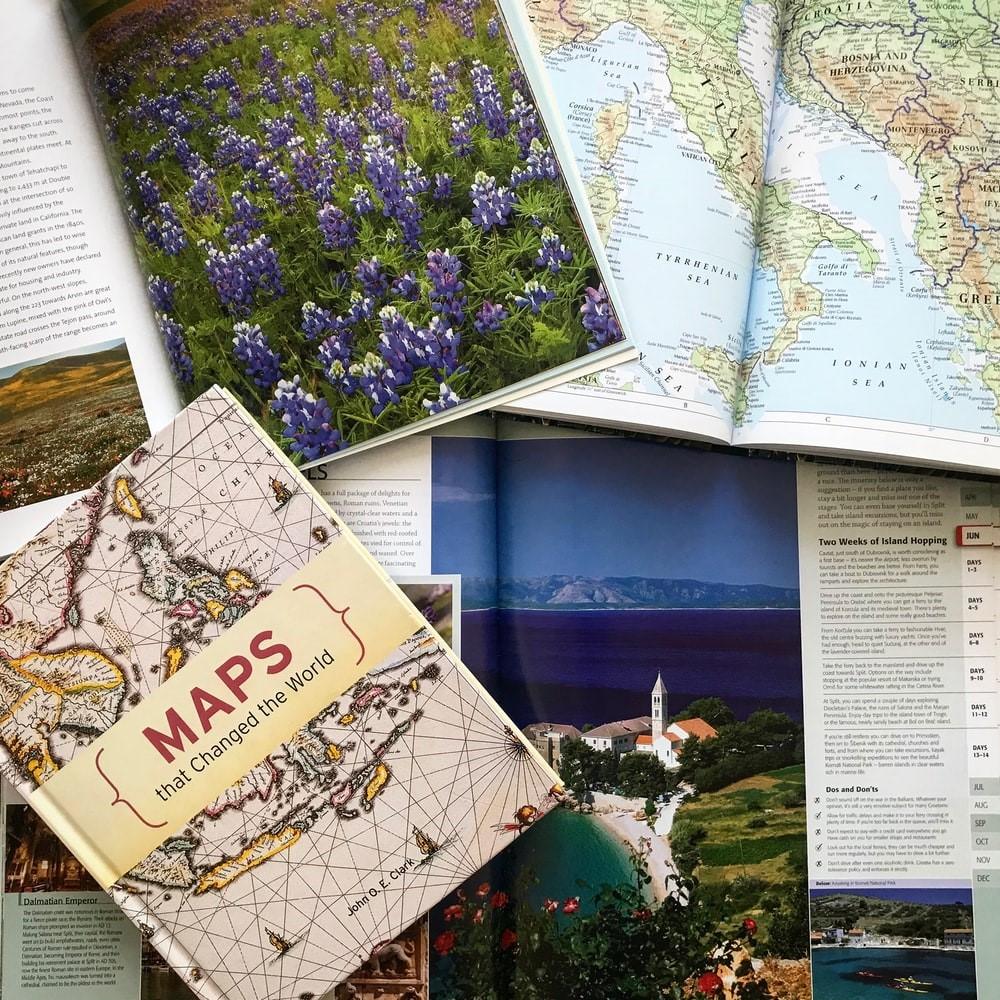 Multiple geographical books laying open on a table