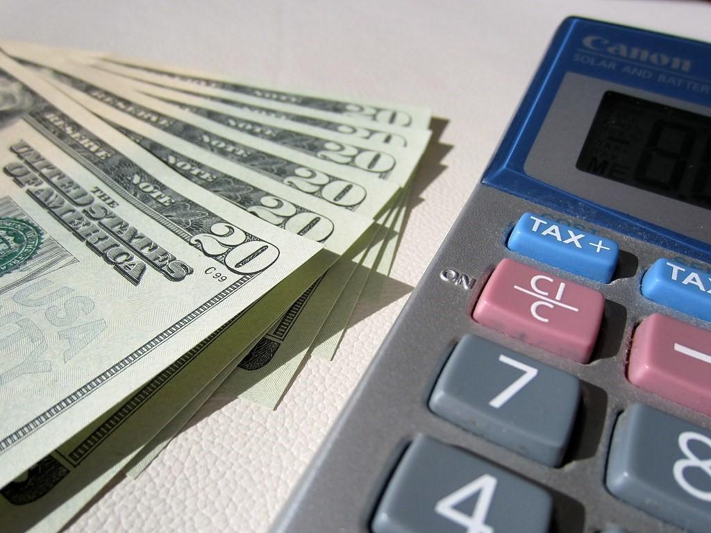 A calculator and twenty-dollar bills set next to each other