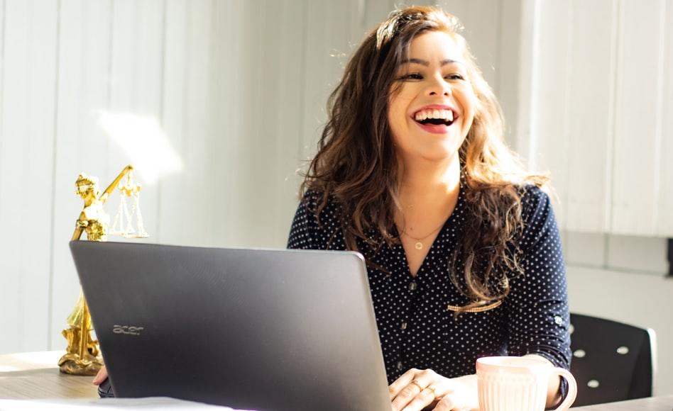 A girl laughing while taking an online lesson on her laptop.