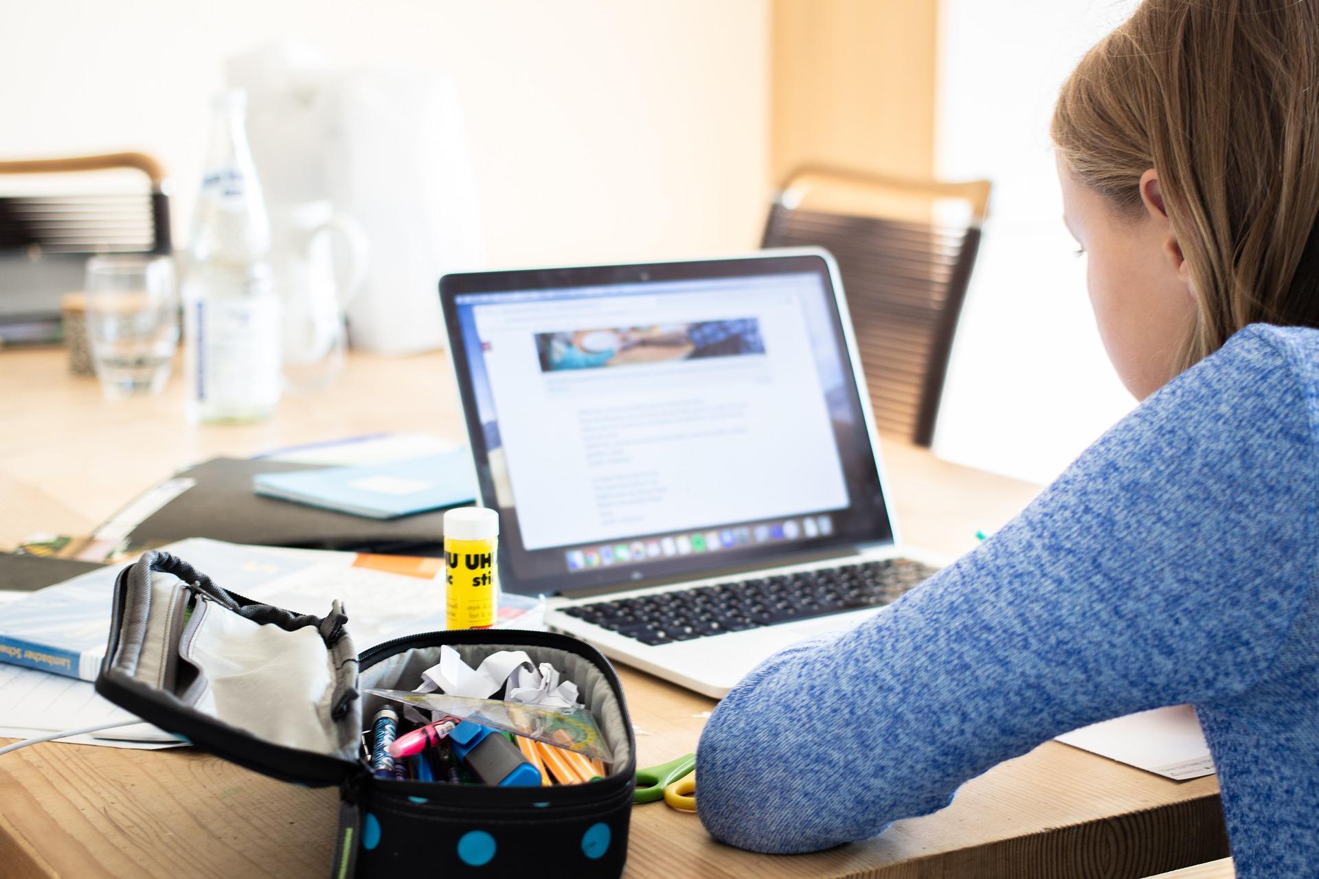 A girl with a laptop and some stationery on a work desk