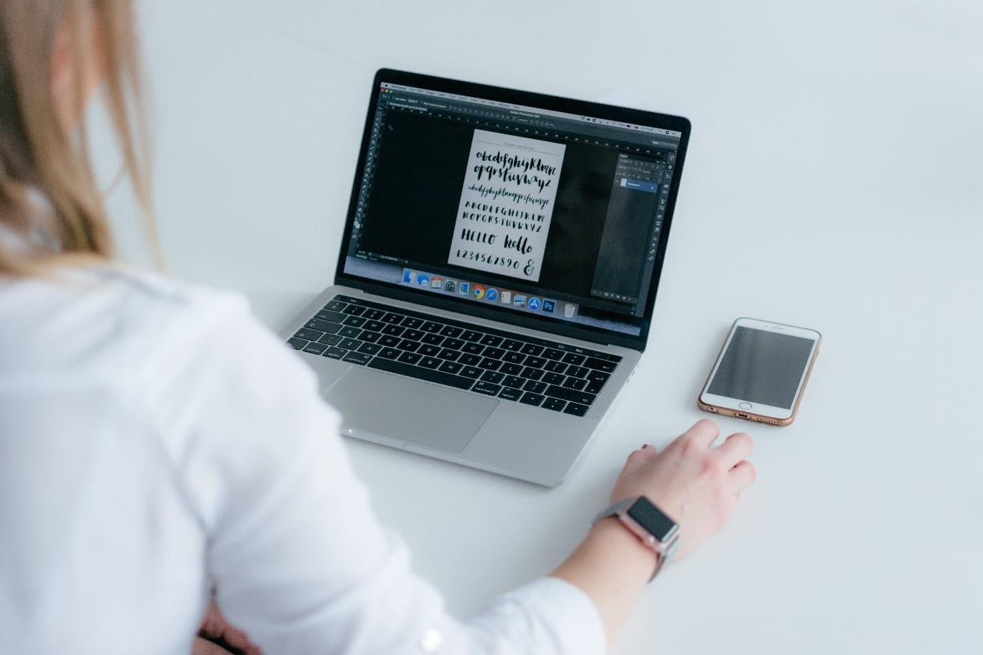A graphic designer working on a project on their laptop.