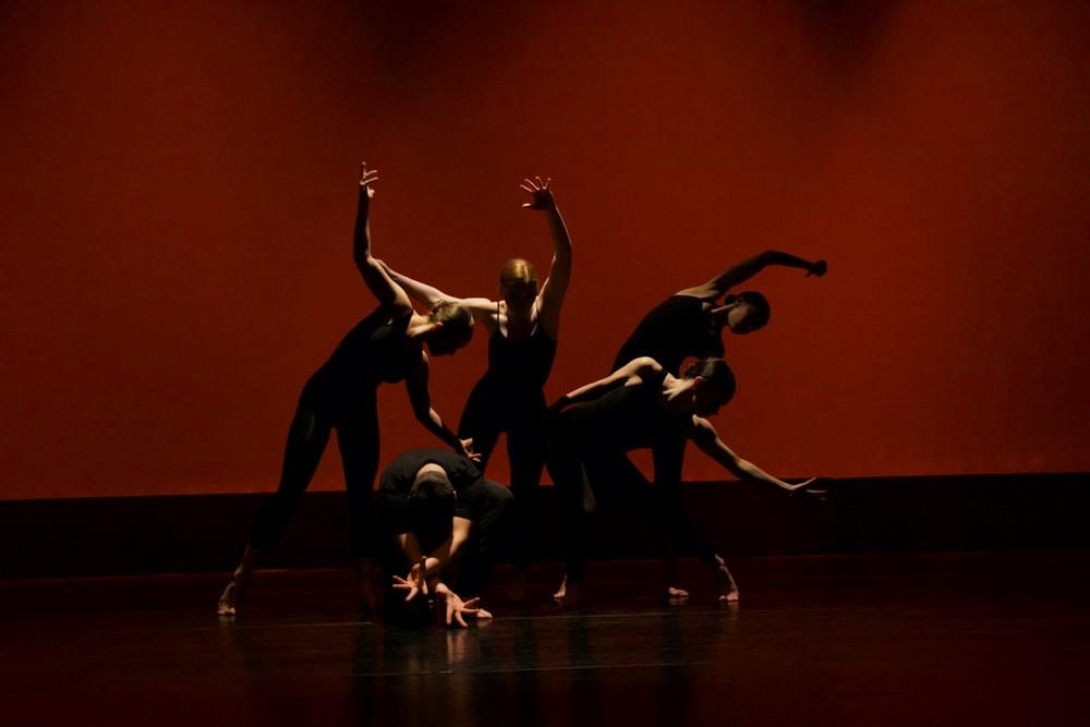 A group of people doing complex ballet dance moves on stage