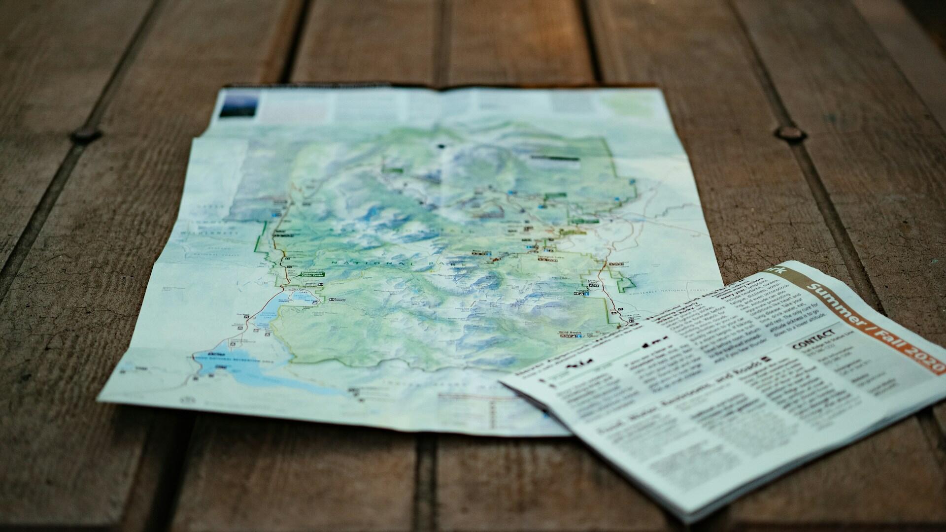 A map and newsletter laid out of a wooden table.