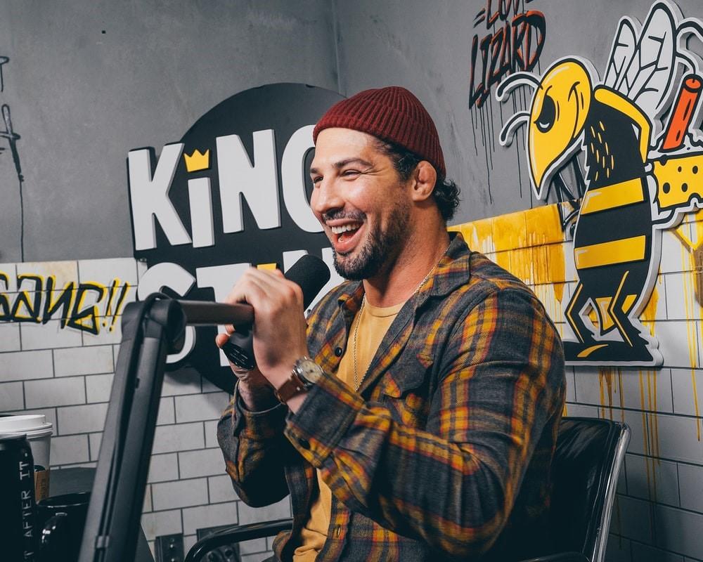 A standup comedian with a red knit cap performs a gig