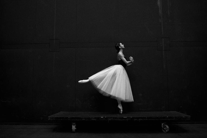 A Ballerina balancing her body on one toe placed on a wheeled board.