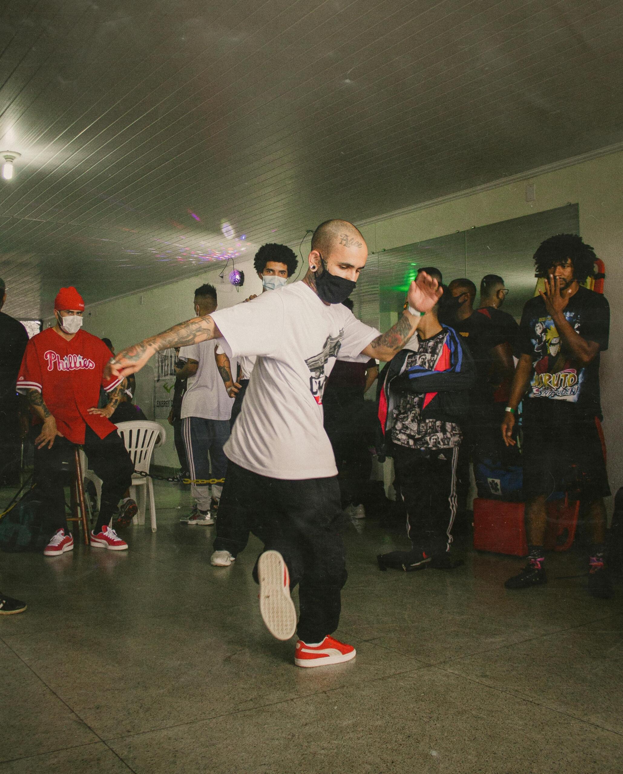 Tattooed man wearing white shirt breakdancing