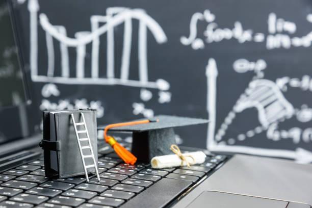 A black graduation cap, a diploma, a white ladder, and a book kept on a table