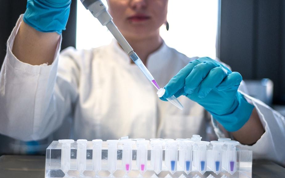 Female scientist pipetting colored chemicals into a tube