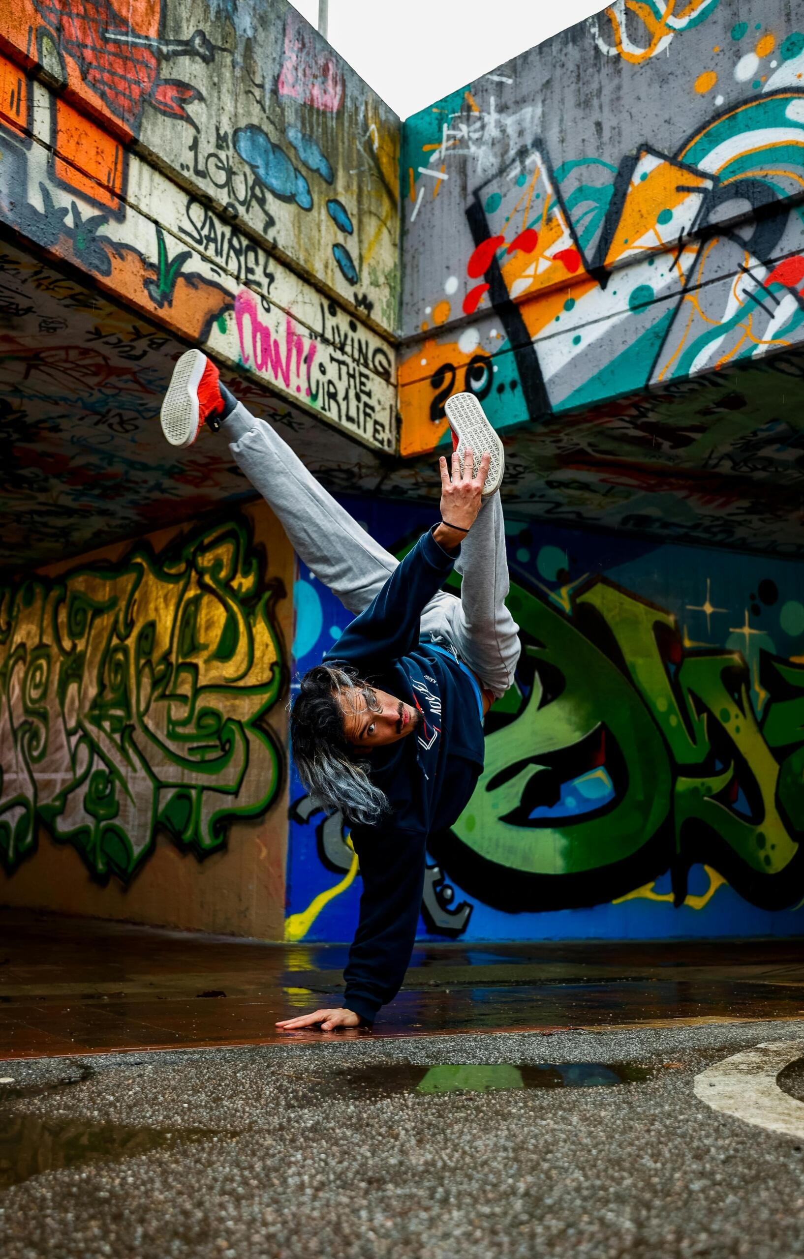Man breakdancing near walls with graffiti