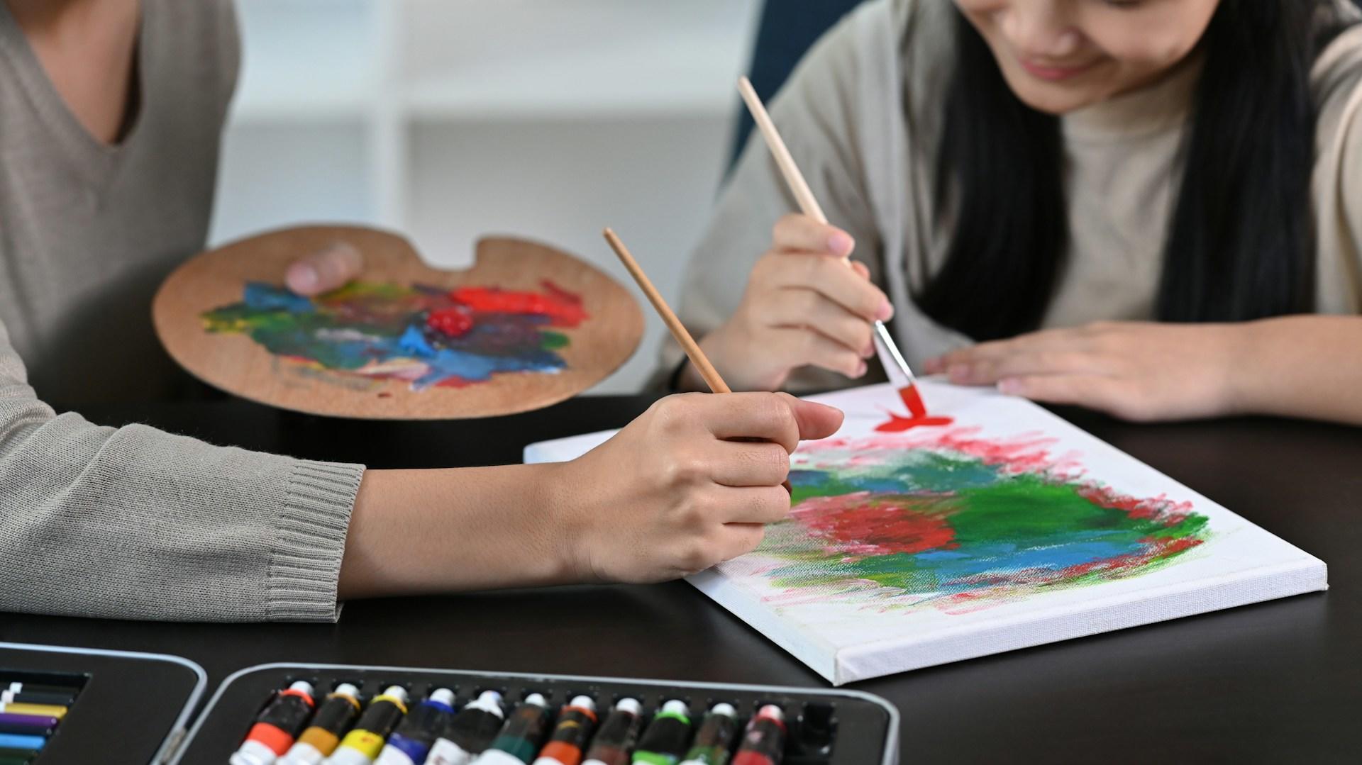 Two people painting on a canvas.