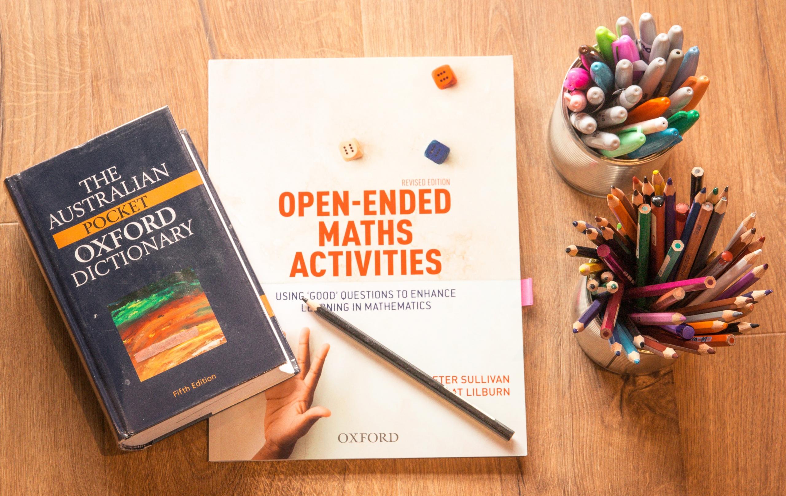 A portrait displaying a collection of color pencils and ballpoints along with Oxford's mathematic book and Oxford's dictionary