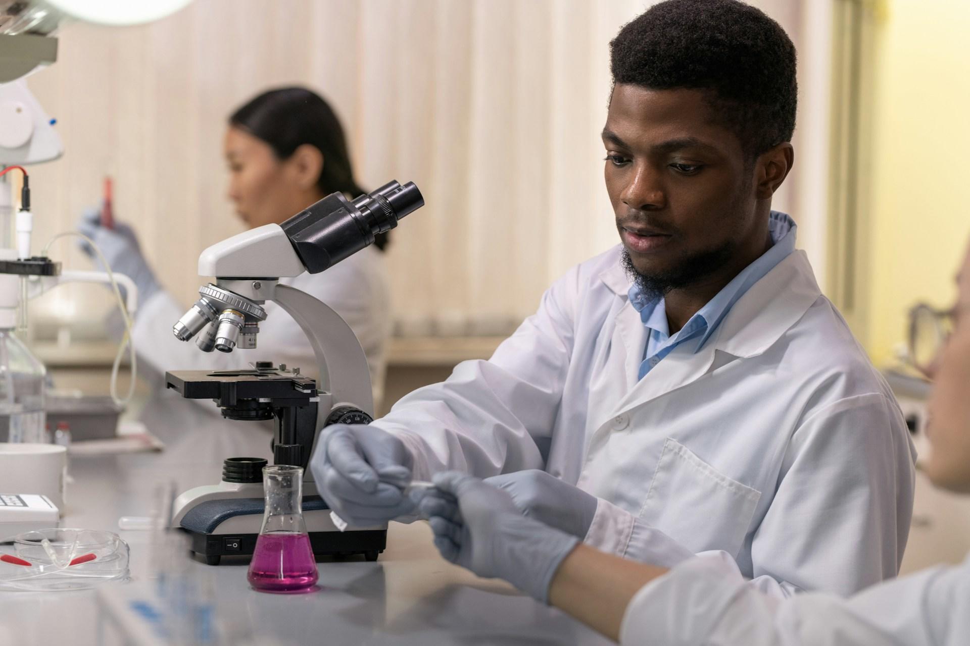 A man in front of a microscope working.