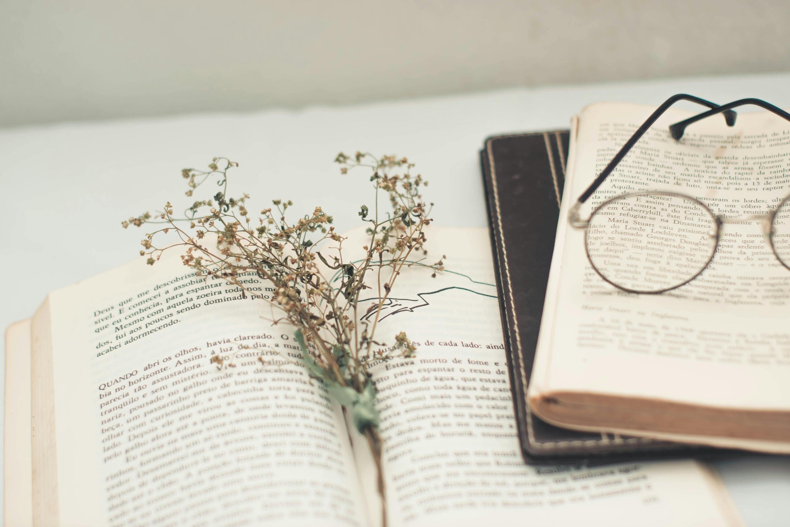 Black-framed eyeglasses resting on an open book with printed text.