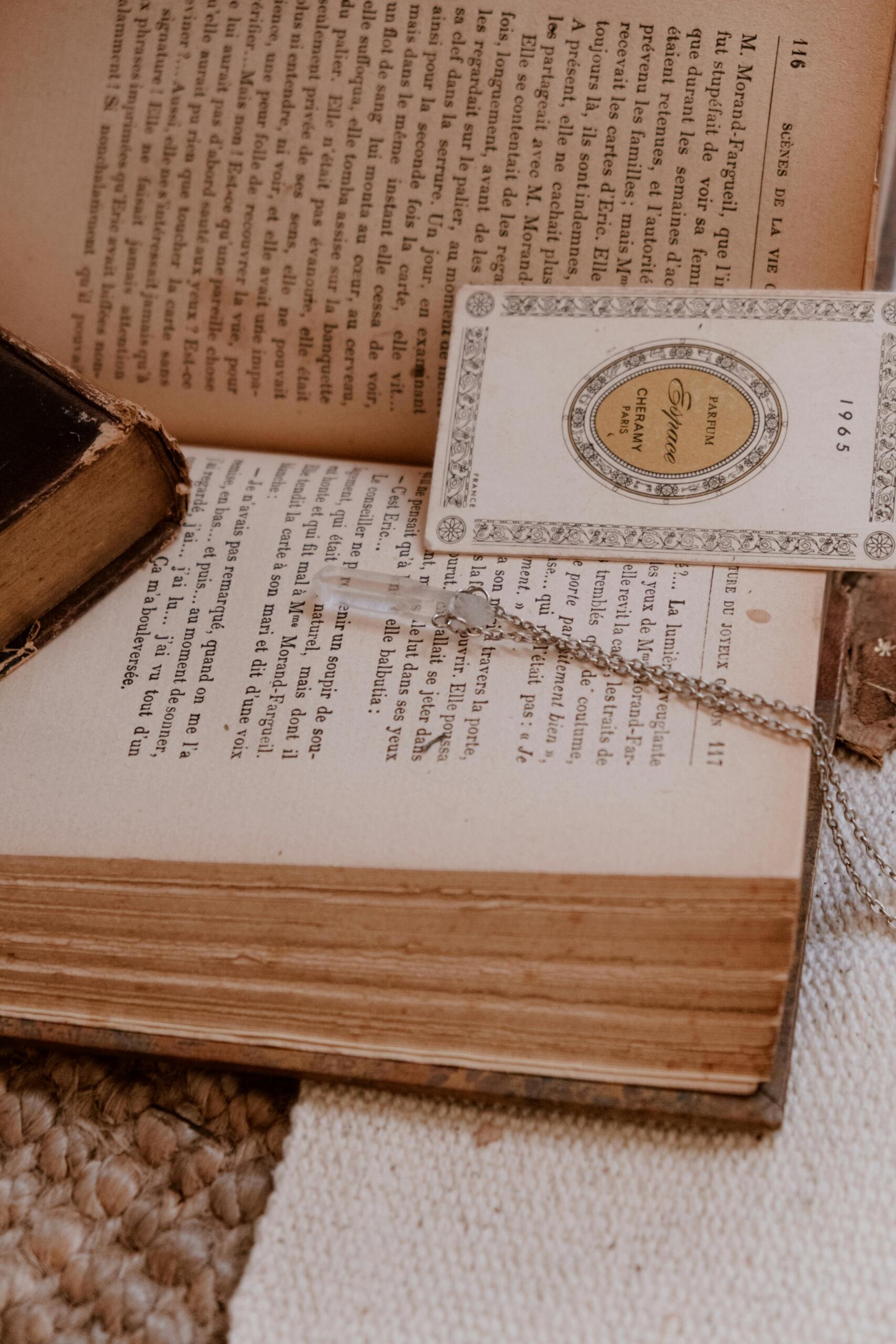 A crystal pendant and a bookmark resting on the yellowed pages of an old book.