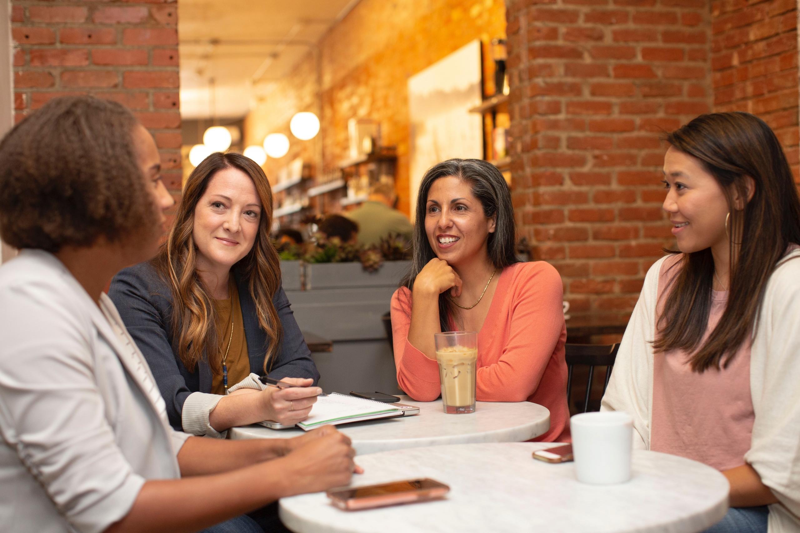 Four women speaking at a table