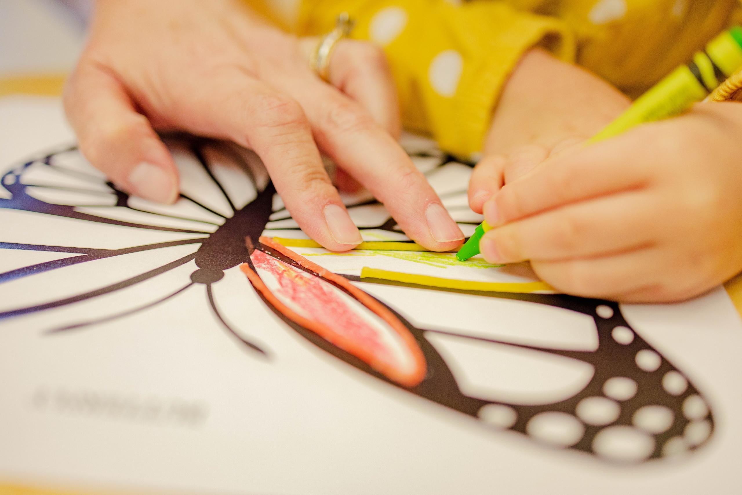 An art tutor helping a student color a butterfly