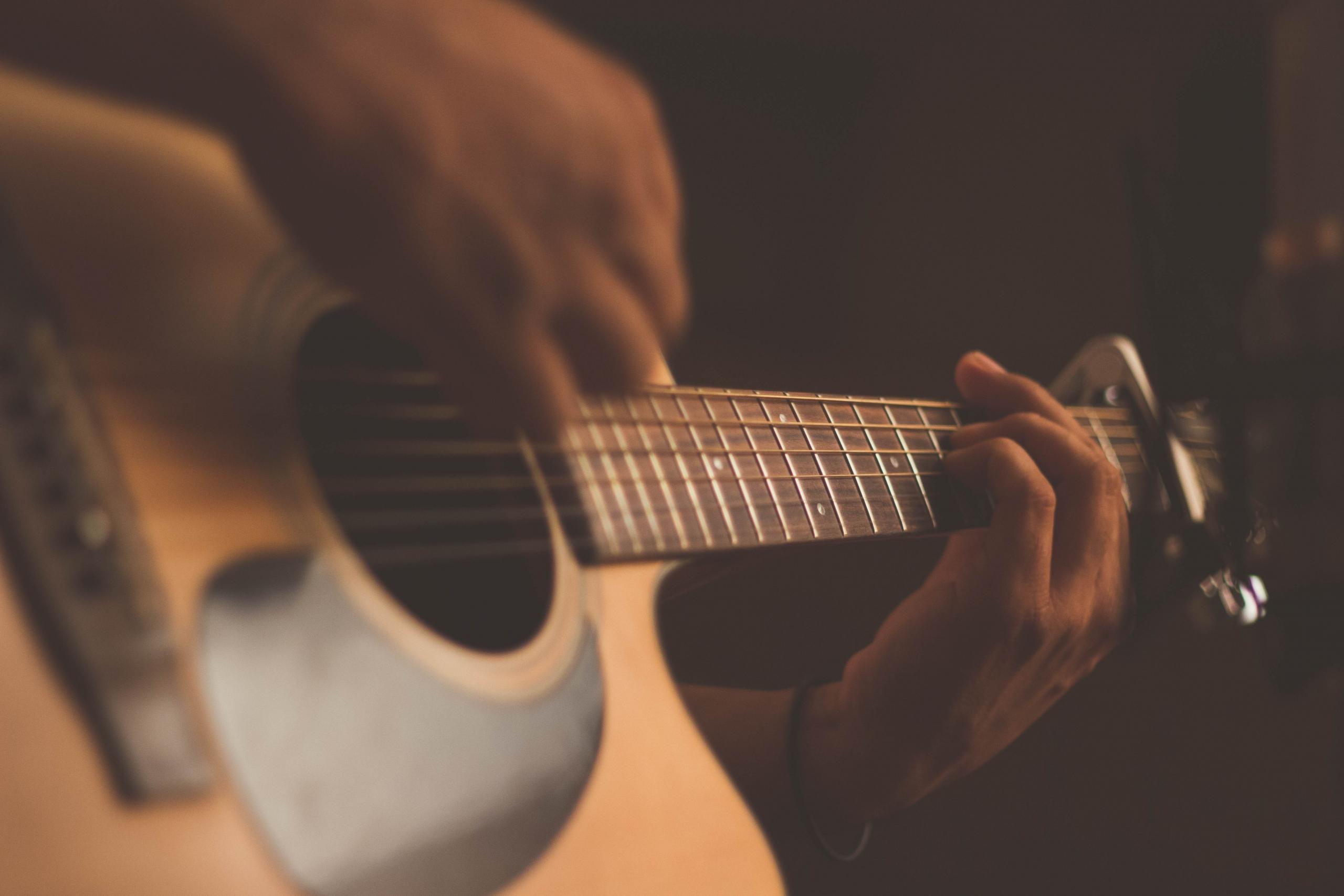 Man strumming a guitar with a pick