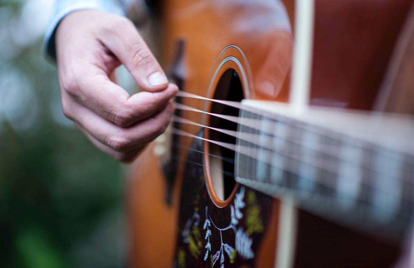 An acoustic guitarist in dim light