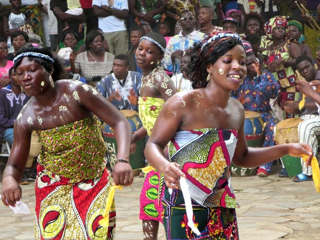 Three girls performing an African dance in colorful clothing.