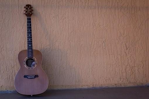 An acoustic guitar resting against the wall