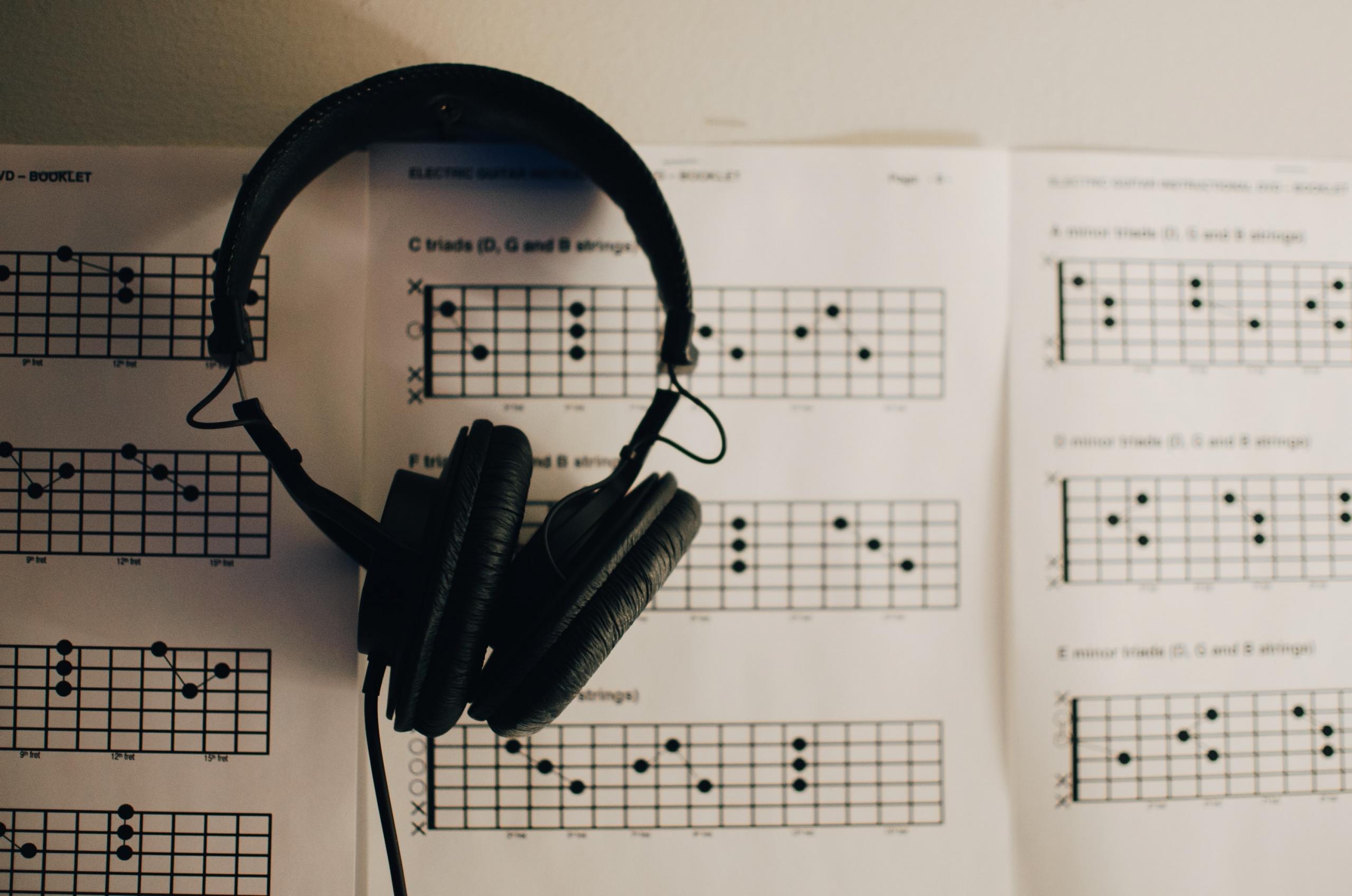 A headphone is placed on chord charts and tablature