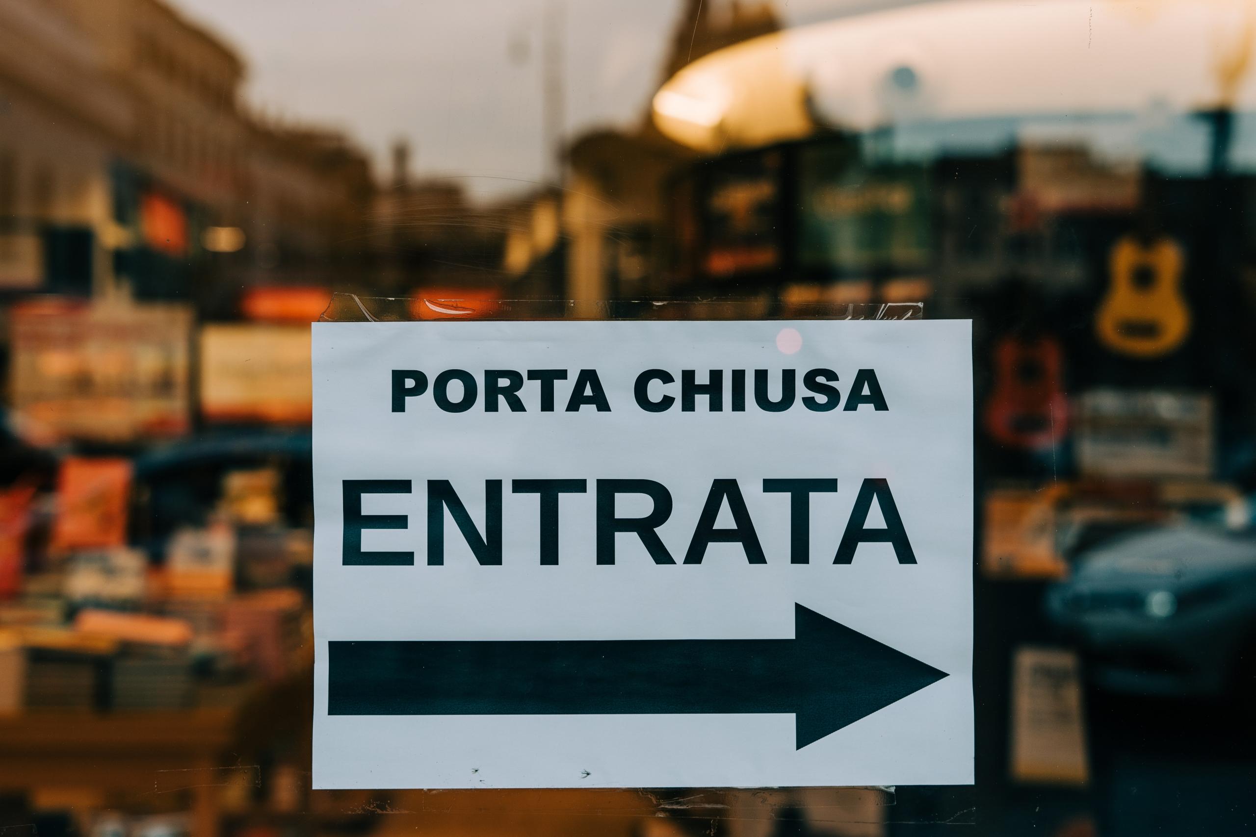 A Signboard of a restaurant in the Italian language saying "Door Closed – Entrance."