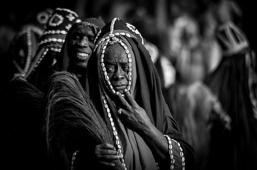 African women in their traditional attire perform a circular ritual dance, with the front one appearing as the head of the group