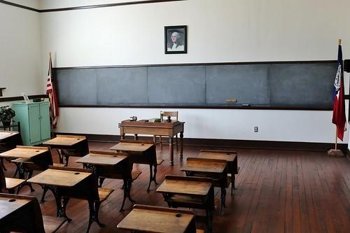 A classroom with empty benches and a blackboard