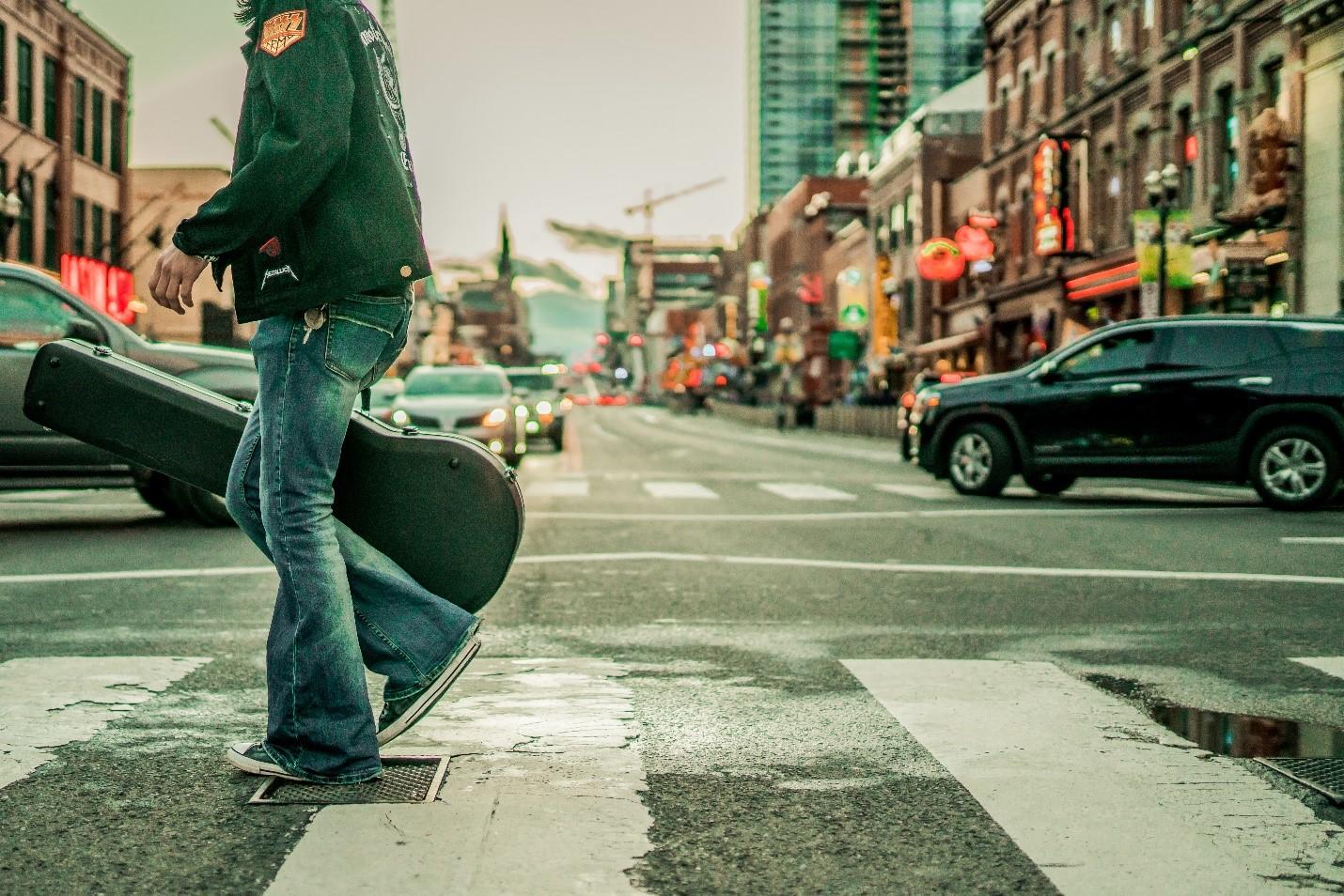 A guitarist crossing a street in Nashville