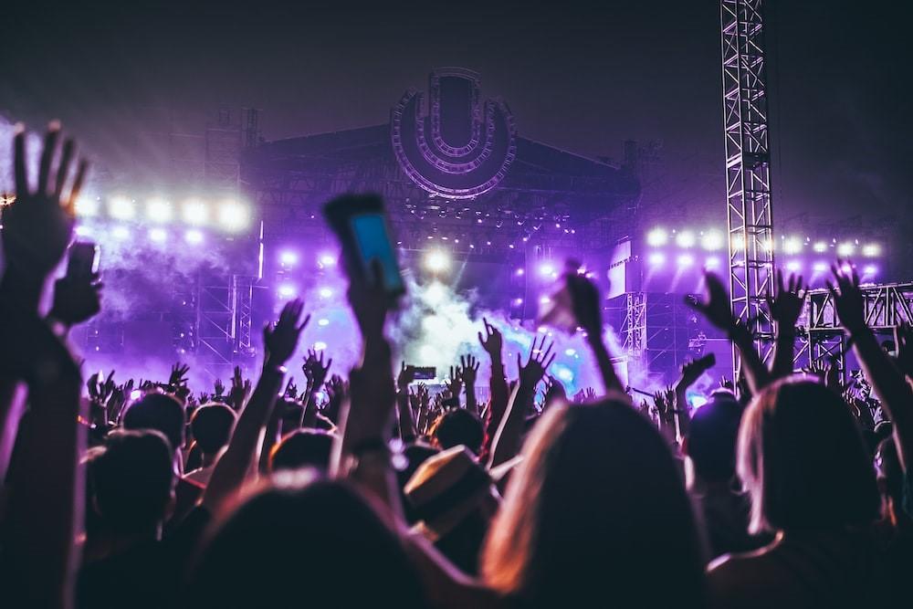 A massive crowd of people holding their phones in the air in a live music festival